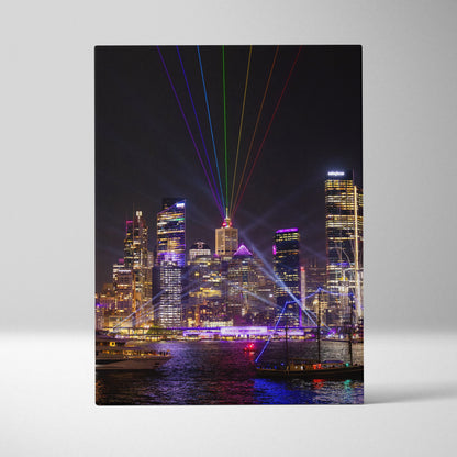 Vertical canvas wall art of vibrant urban skyline at night with colorful laser lights.