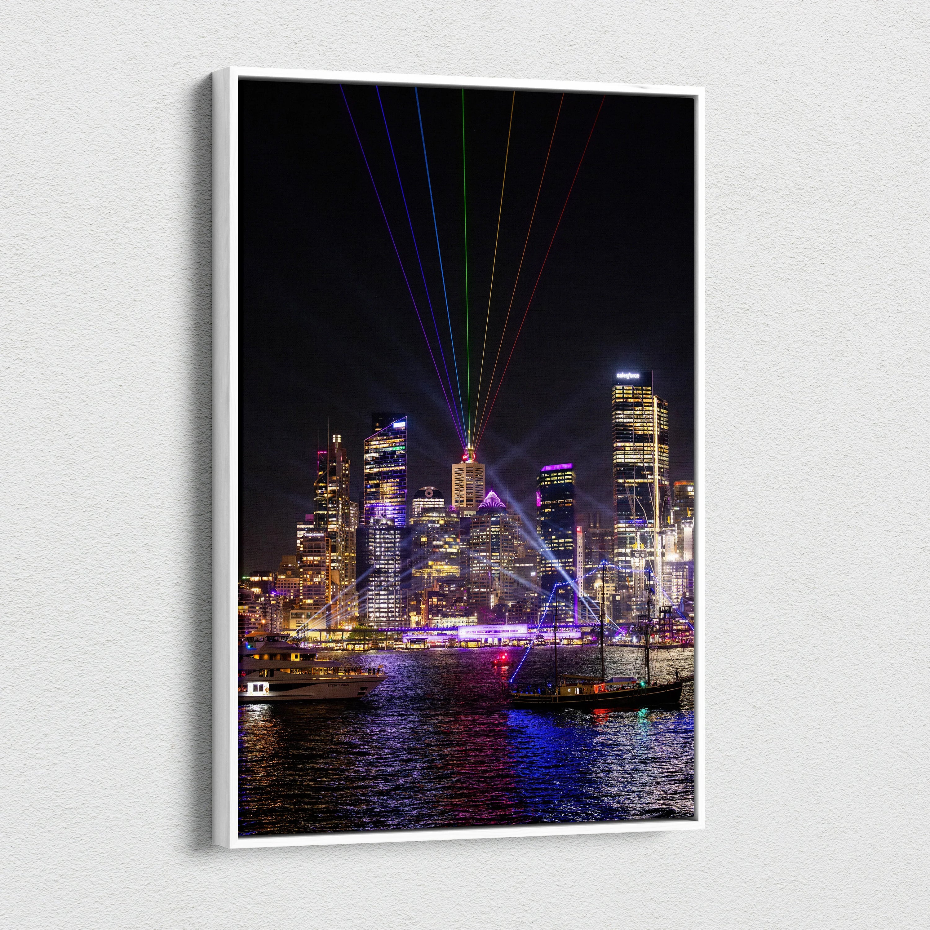 Vertical canvas wall art of illuminated urban skyline with colorful laser lights over water at night.