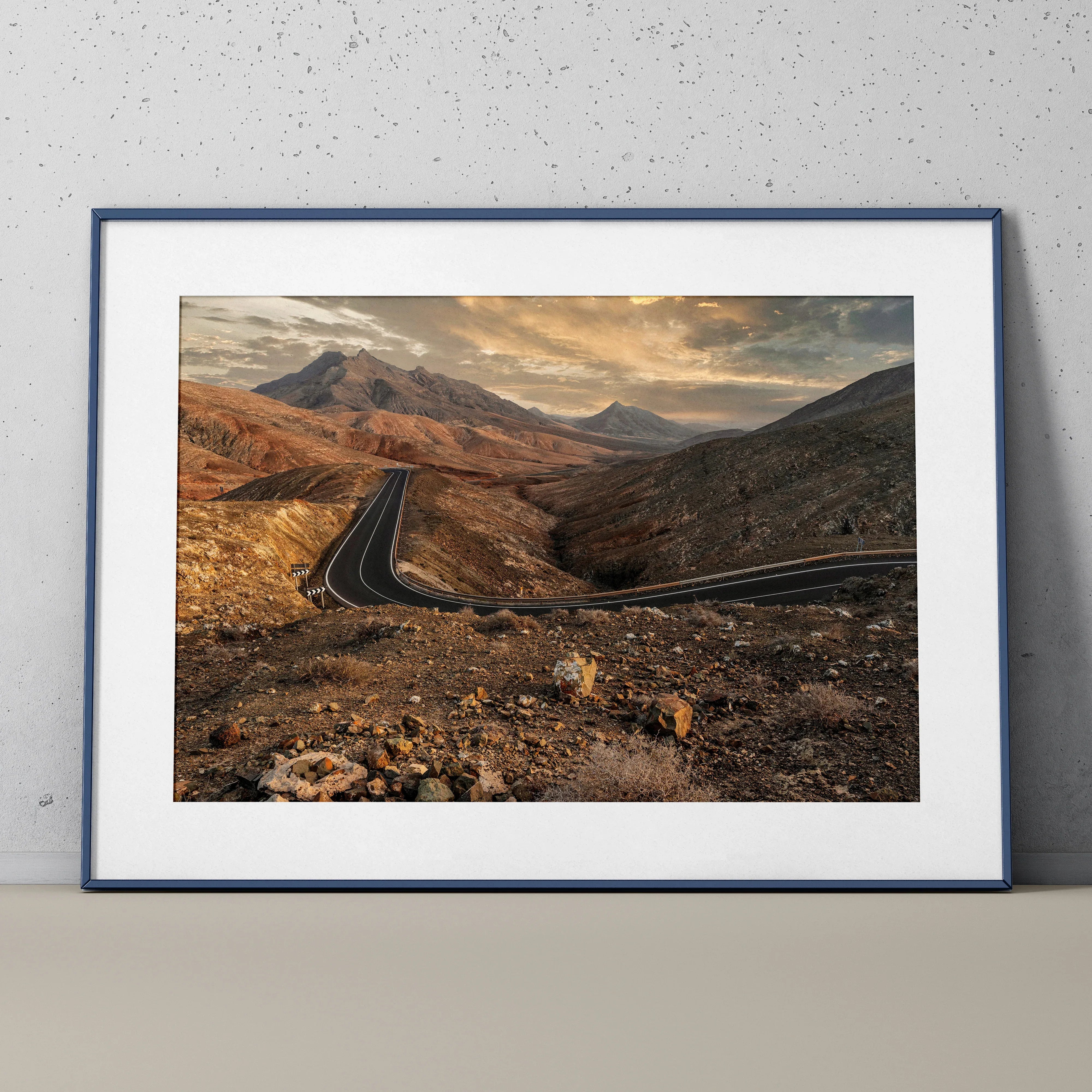 Mountain landscape wall art poster featuring winding road under dramatic sunset sky.
