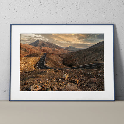 Mountain landscape wall art poster featuring winding road under dramatic sunset sky.