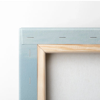 Close-up of canvas wall art corner showing light wood frame and blue fabric backing with stapled edges.