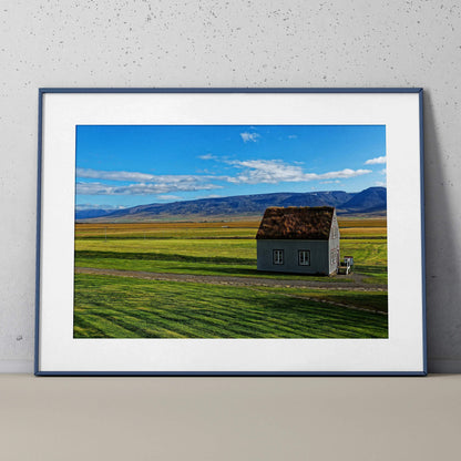 Modern architectural building wall art poster featuring a solitary house on a vast green field under a bright blue sky.