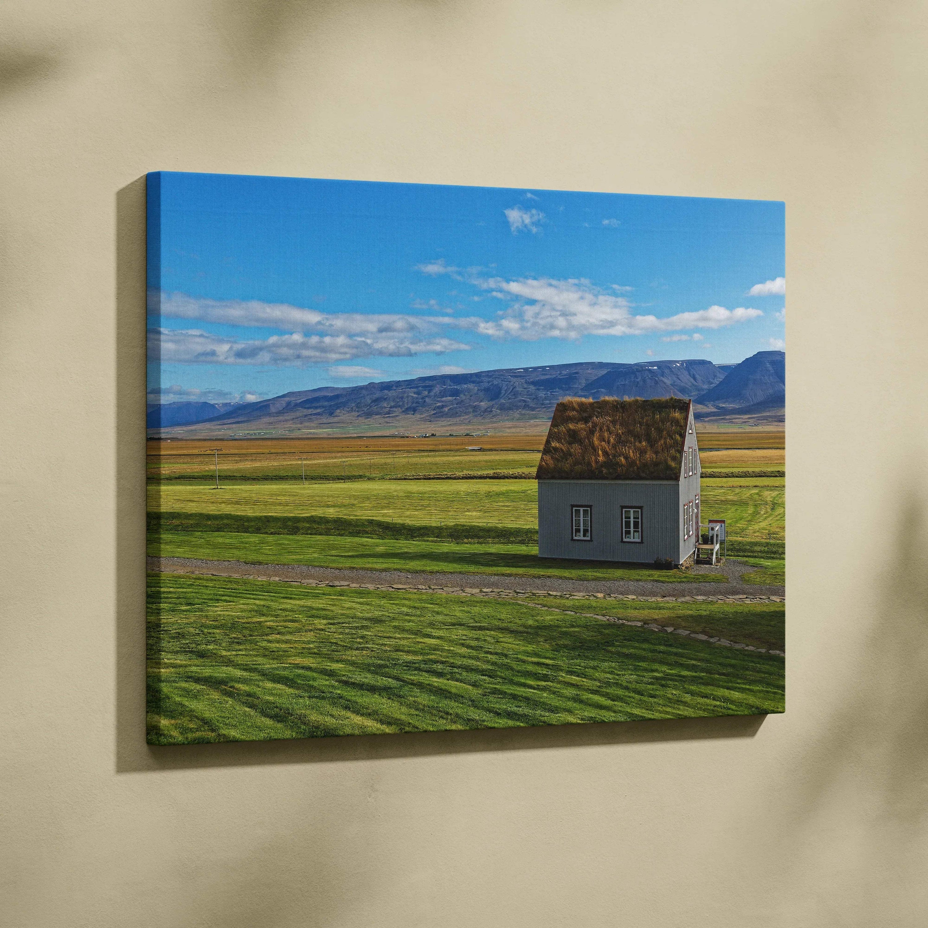 Canvas wall art featuring a solitary rustic house in a vast green field under a blue sky with scattered clouds.