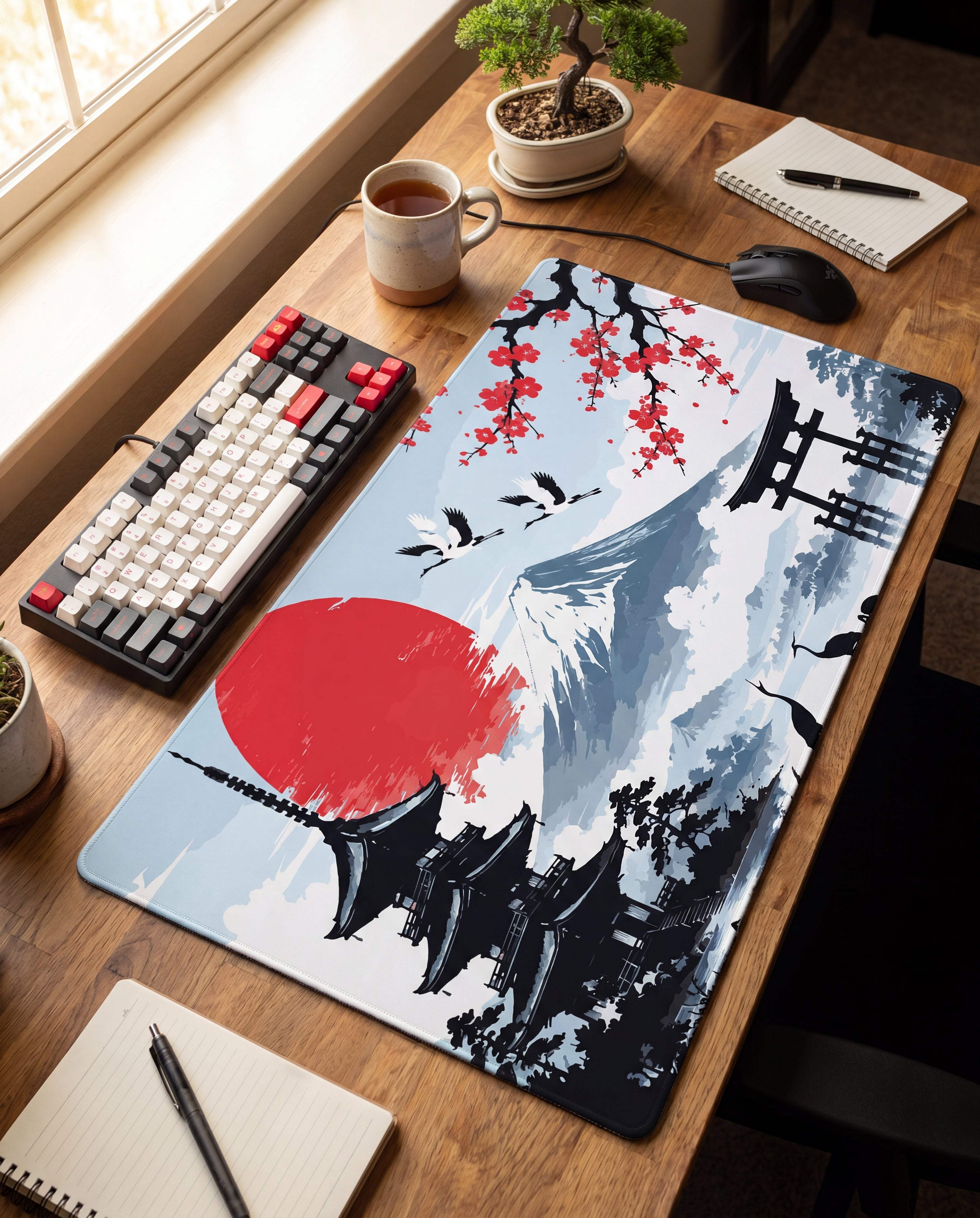 A rectangular gaming mousepad featuring a stylized japanese landscape with red cherry blossoms, black pagoda silhouettes, and a prominent red sun against a light blue sky.