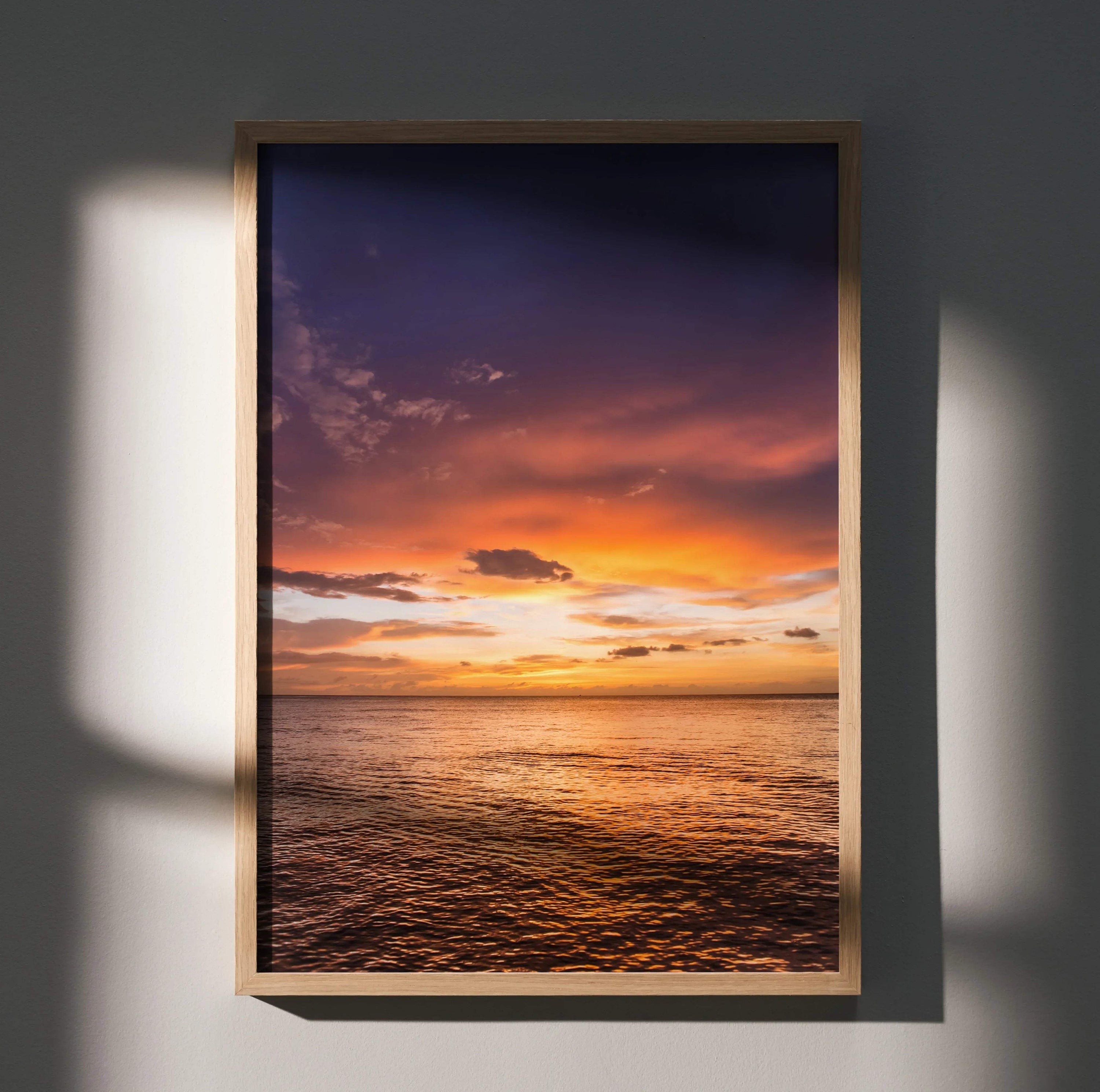 Ocean sunset poster with vibrant orange and purple sky reflected on calm water, vertical wall art in wooden frame.