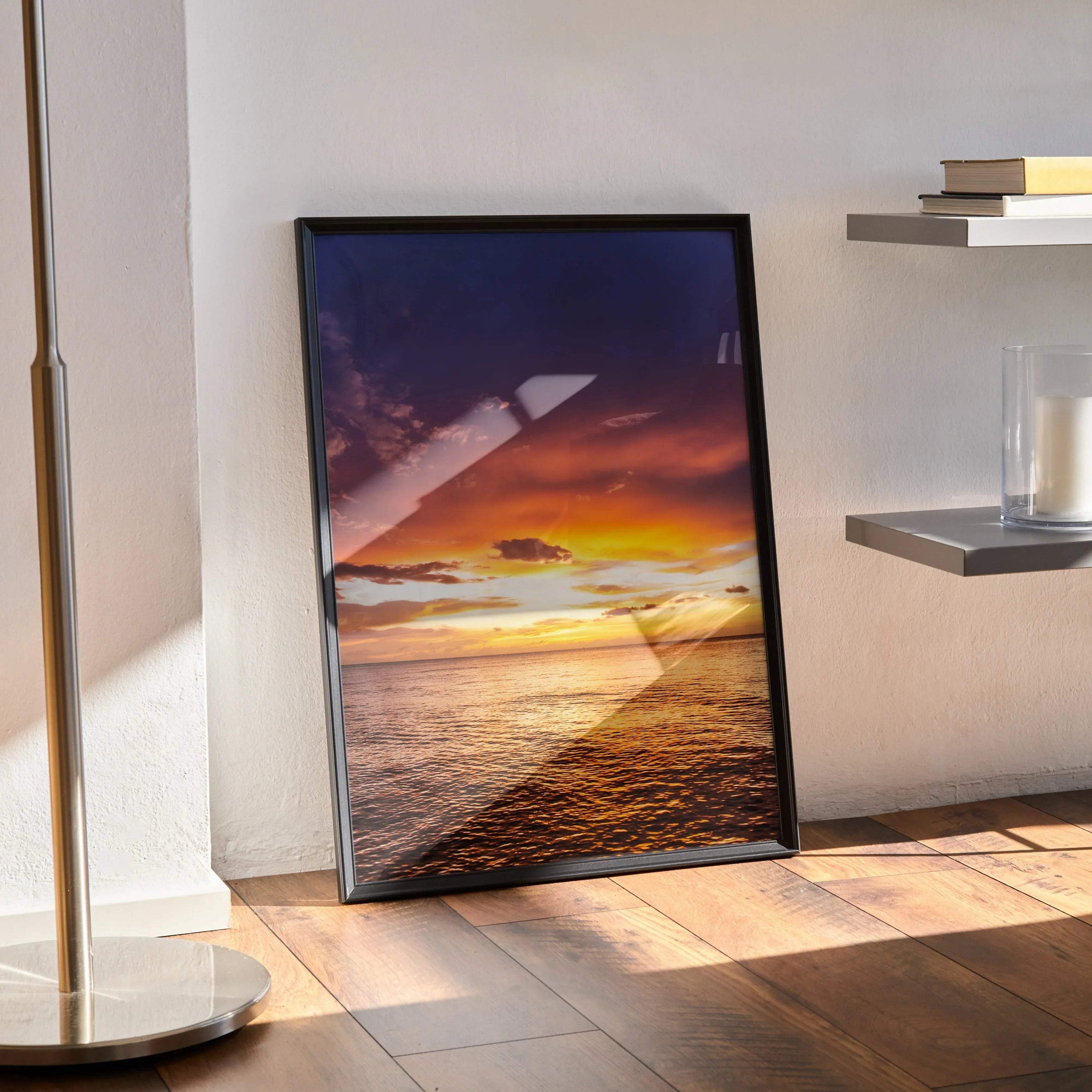 Ocean sunset poster with vibrant orange and purple sky reflecting over calm water, vertical wall art in black frame.