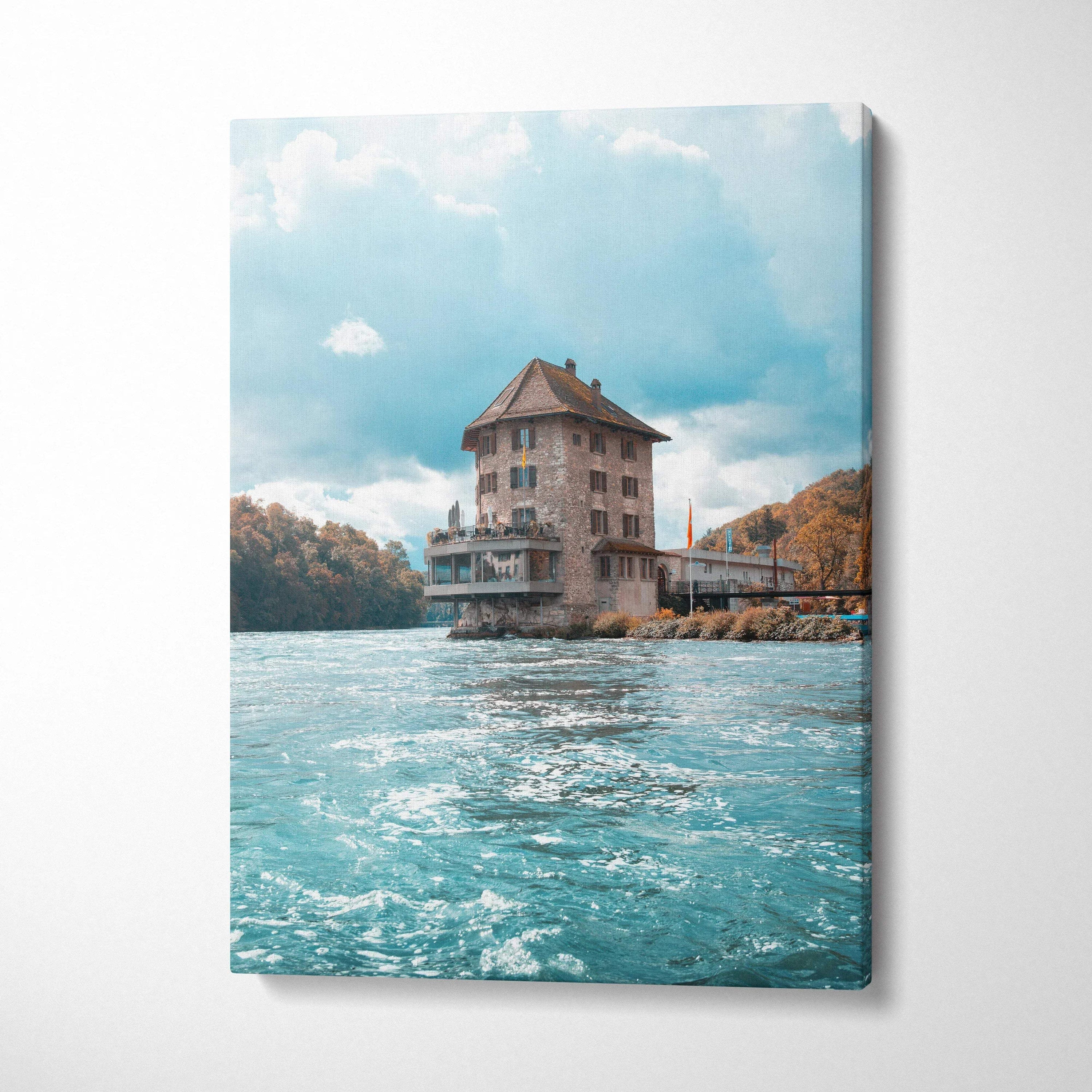 Vertical canvas wall art featuring rustic building on water under blue sky.