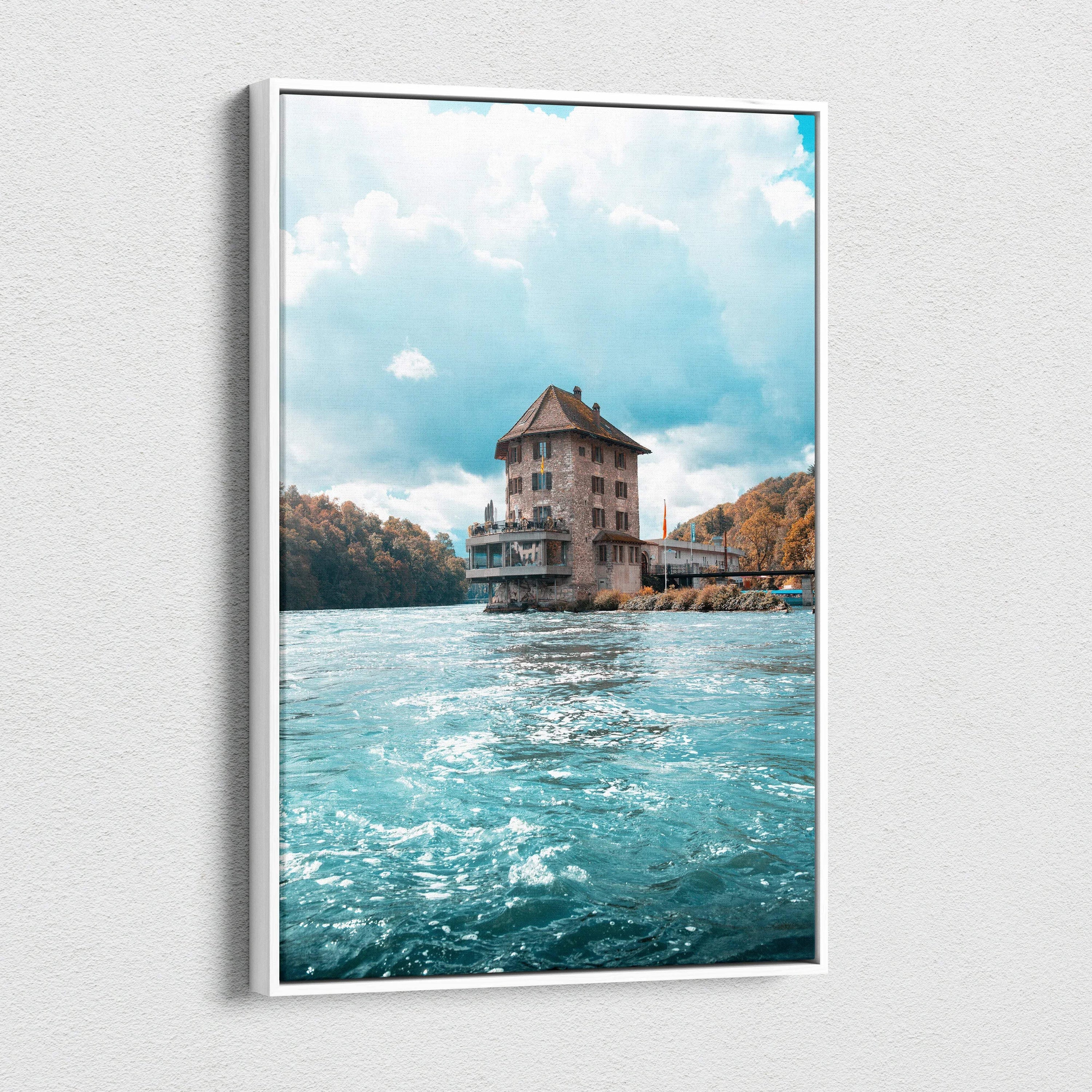 Vertical canvas wall art of a large house on water with a cloudy sky background.