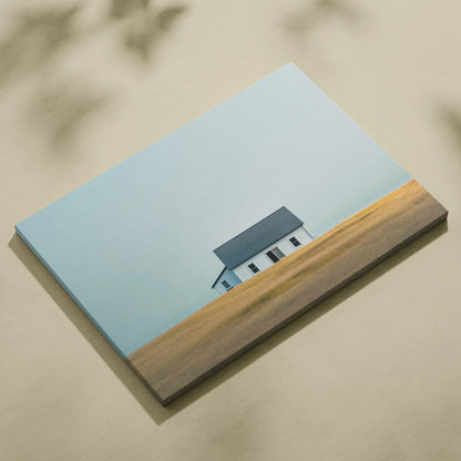 Minimalist canvas wall art featuring a small house against a clear blue sky and golden field.