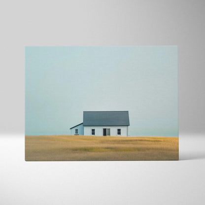 Minimalist canvas wall art featuring a solitary white house with a dark roof in a golden field under a pale blue sky.