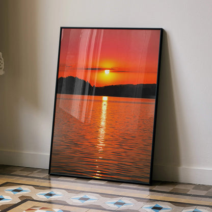 Vertical wall art poster featuring a serene orange and red ocean sunset over calm water with silhouetted landforms.