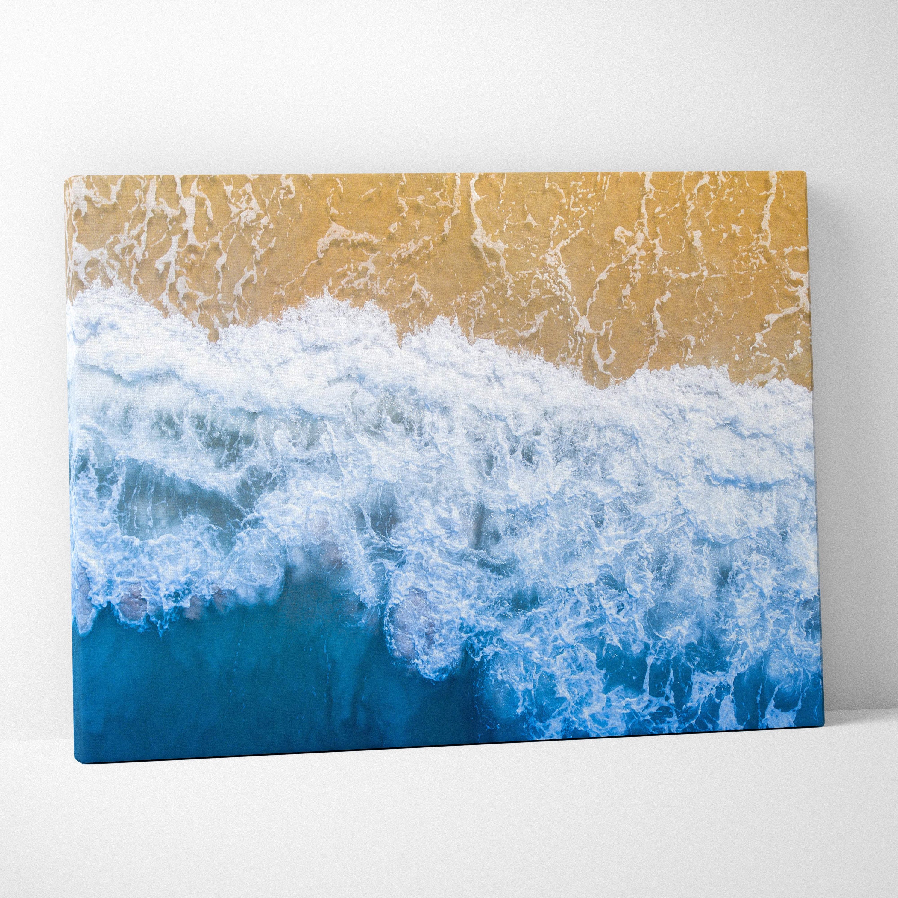Aerial ocean shore canvas wall art print showing vibrant blue waves crashing on sandy beach for coastal decor