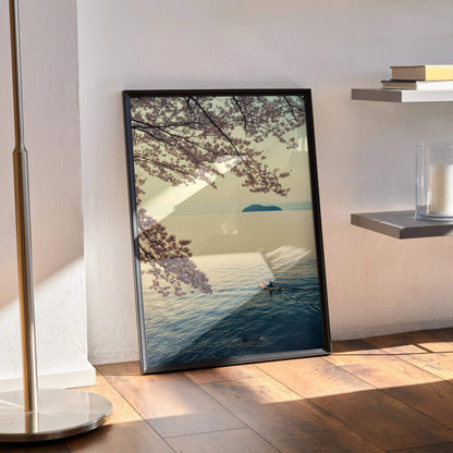 Serene ocean and cherry blossom branches poster wall art with soft pastel colors in black frame.