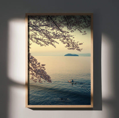 Vertical wall art poster of serene ocean scene with cherry blossom branches and lone kayaker at sunset.