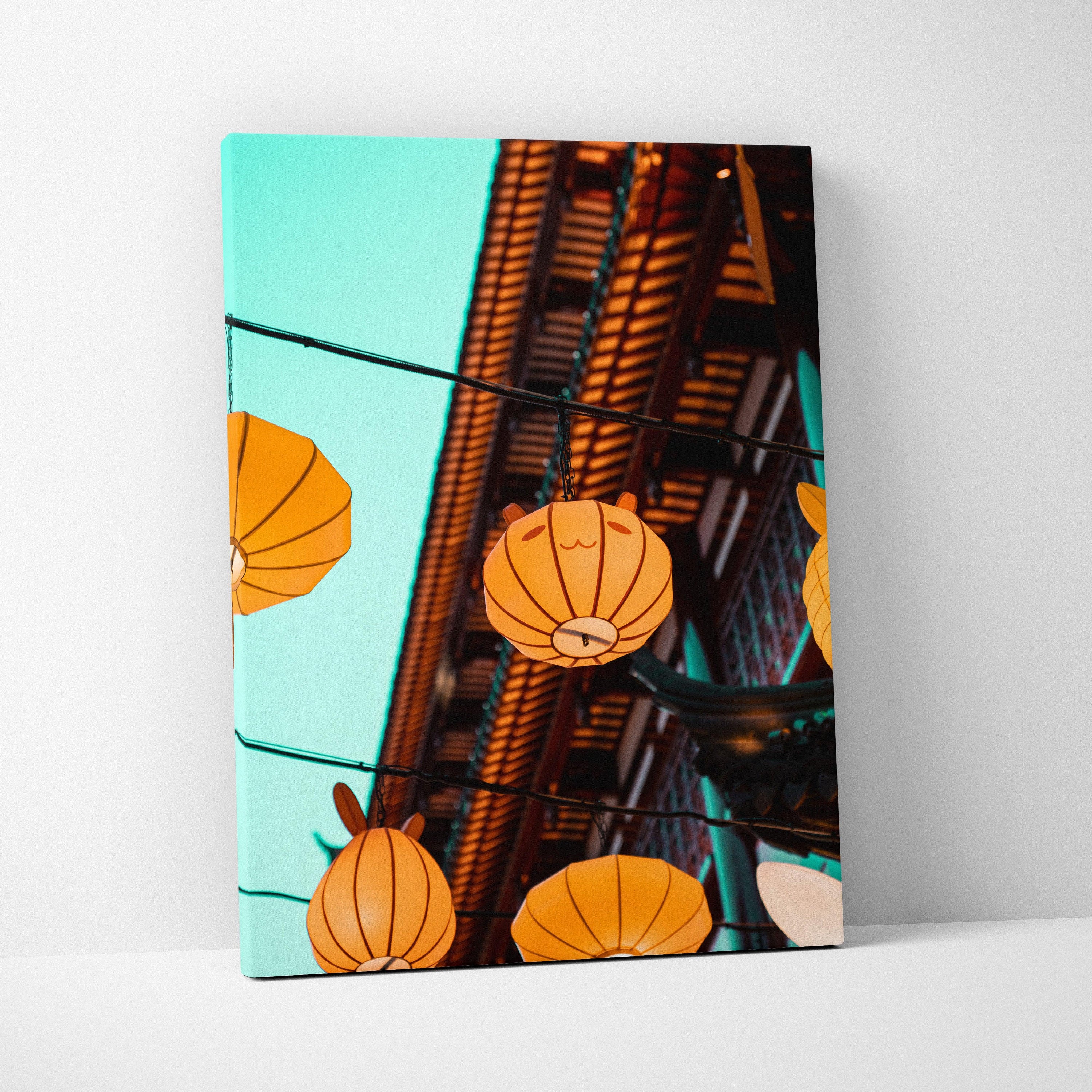 Vertical canvas wall art featuring glowing orange lanterns hanging against a bright turquoise sky.