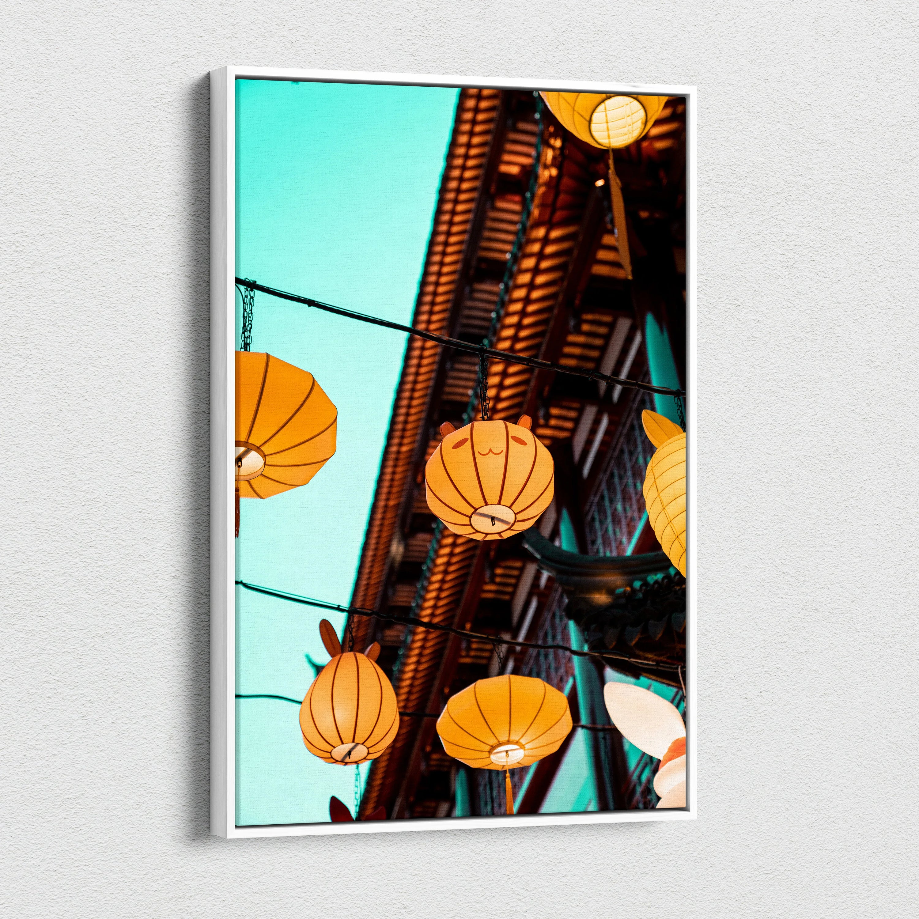 Canvas wall art featuring glowing orange paper lanterns hanging against a bright blue sky and rustic wooden eaves.