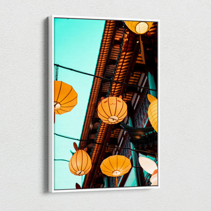 Canvas wall art featuring glowing orange paper lanterns hanging against a bright blue sky and rustic wooden eaves.