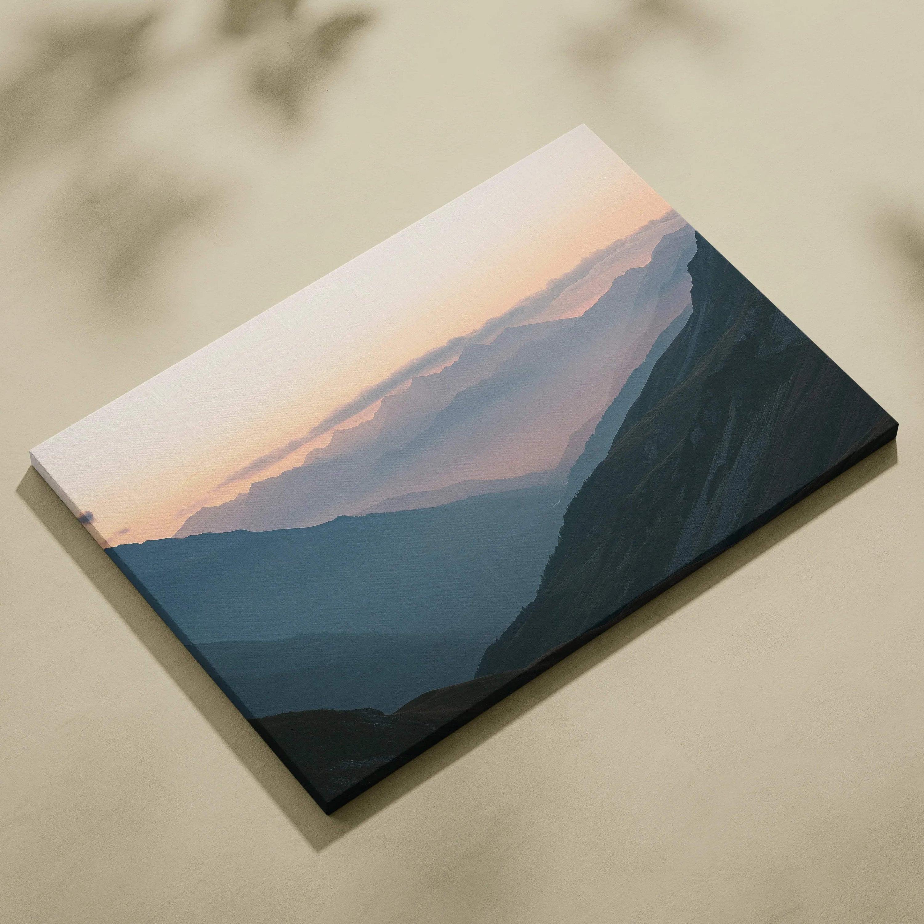 Atmospheric mountain landscape canvas print with misty valleys at dawn in muted blues, teal shadows, and soft peach sky