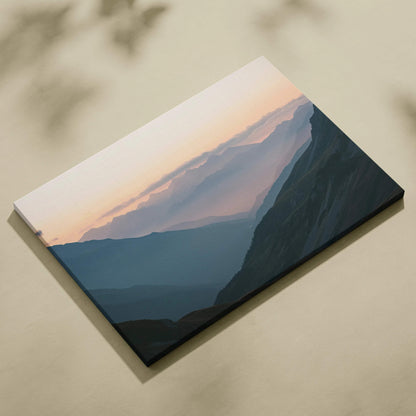 Atmospheric mountain landscape canvas print with misty valleys at dawn in muted blues, teal shadows, and soft peach sky