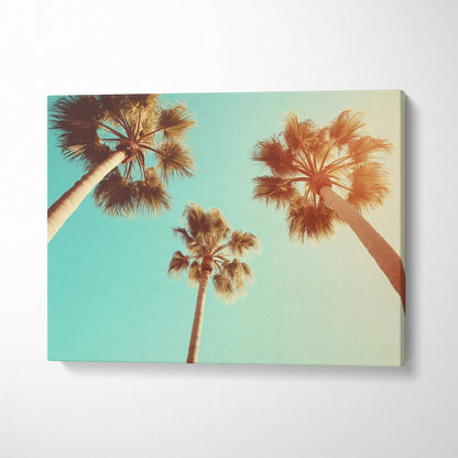 Canvas wall art featuring three tall palm trees against a soft blue sky with warm sunlight glow.