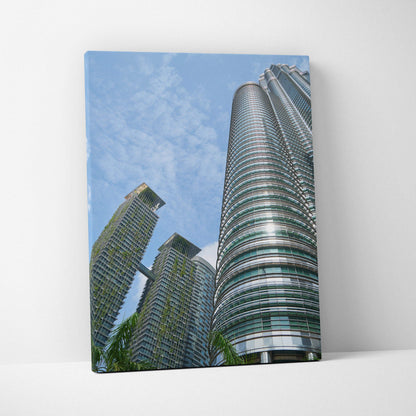 Vertical canvas wall art featuring modern skyscrapers under a blue sky with light clouds.