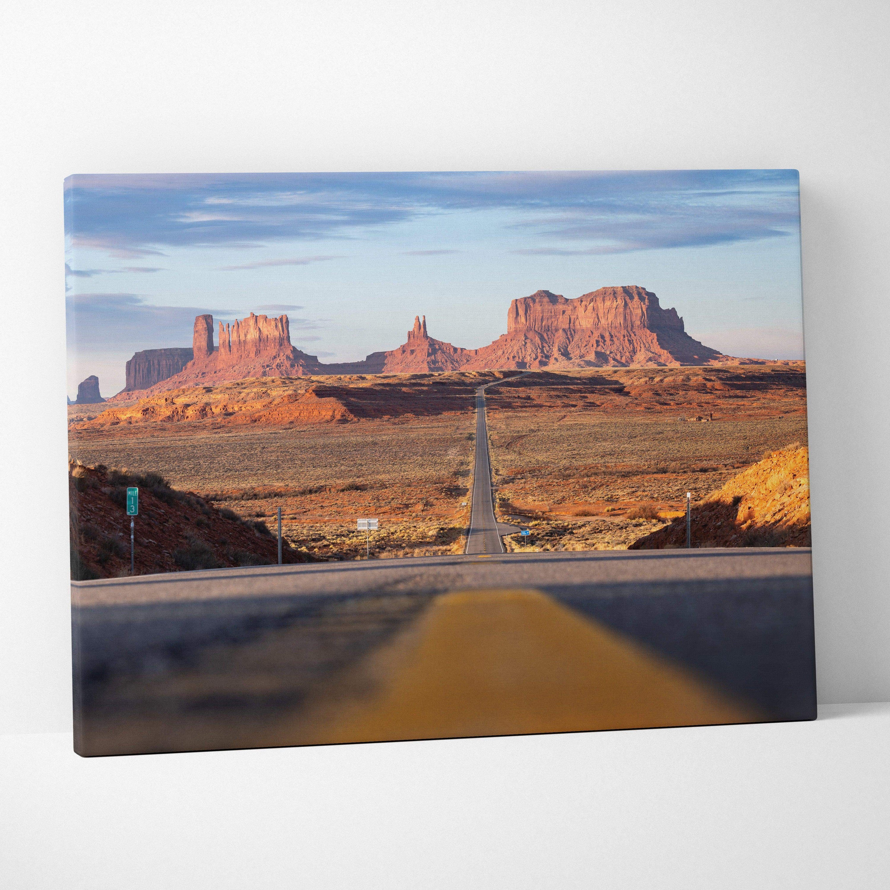 Desert landscape canvas wall art featuring a long road leading to red rock formations under a blue sky.