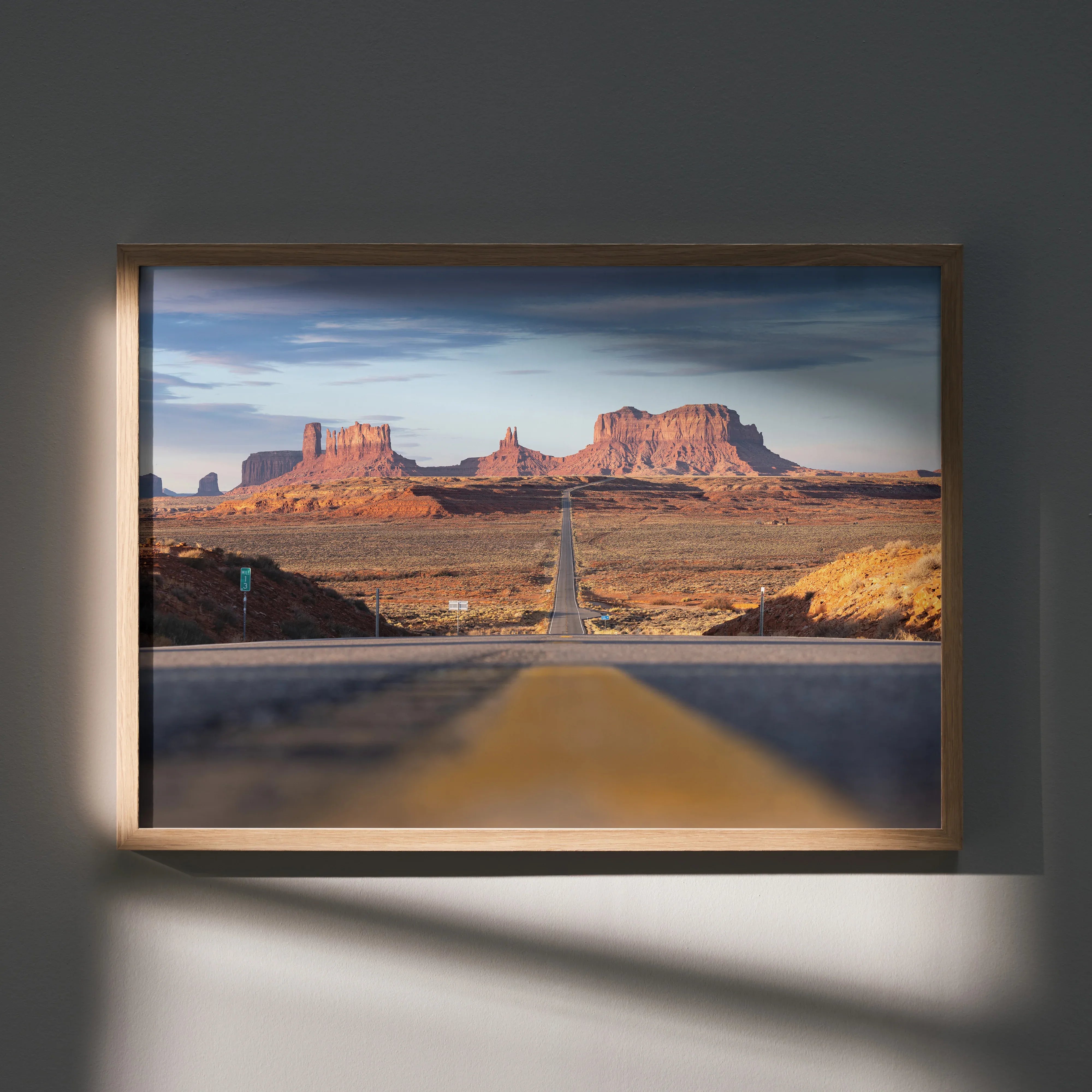 Majestic mountain landscape poster with open desert road, warm tones wall art in wooden frame.
