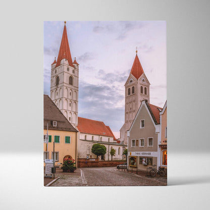 Urban skyline canvas wall art featuring historic buildings with red roofs and church towers under a cloudy sky.