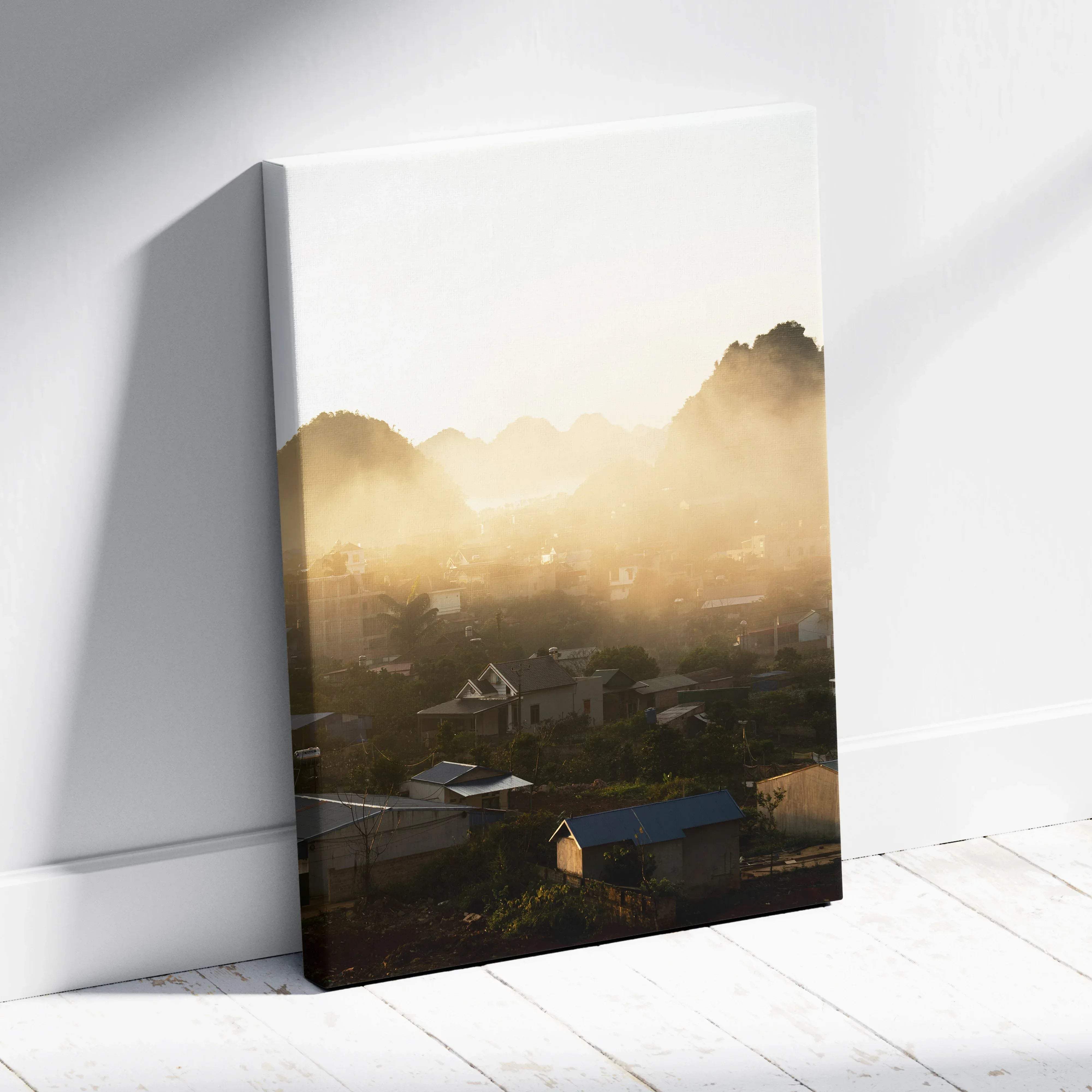 A canvas wall art print of a misty morning mountain ridge landscape glowing golden over a village at sunrise