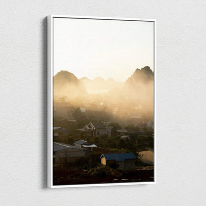 Vertical canvas wall art featuring a misty mountain landscape with soft sunlight and village rooftops.