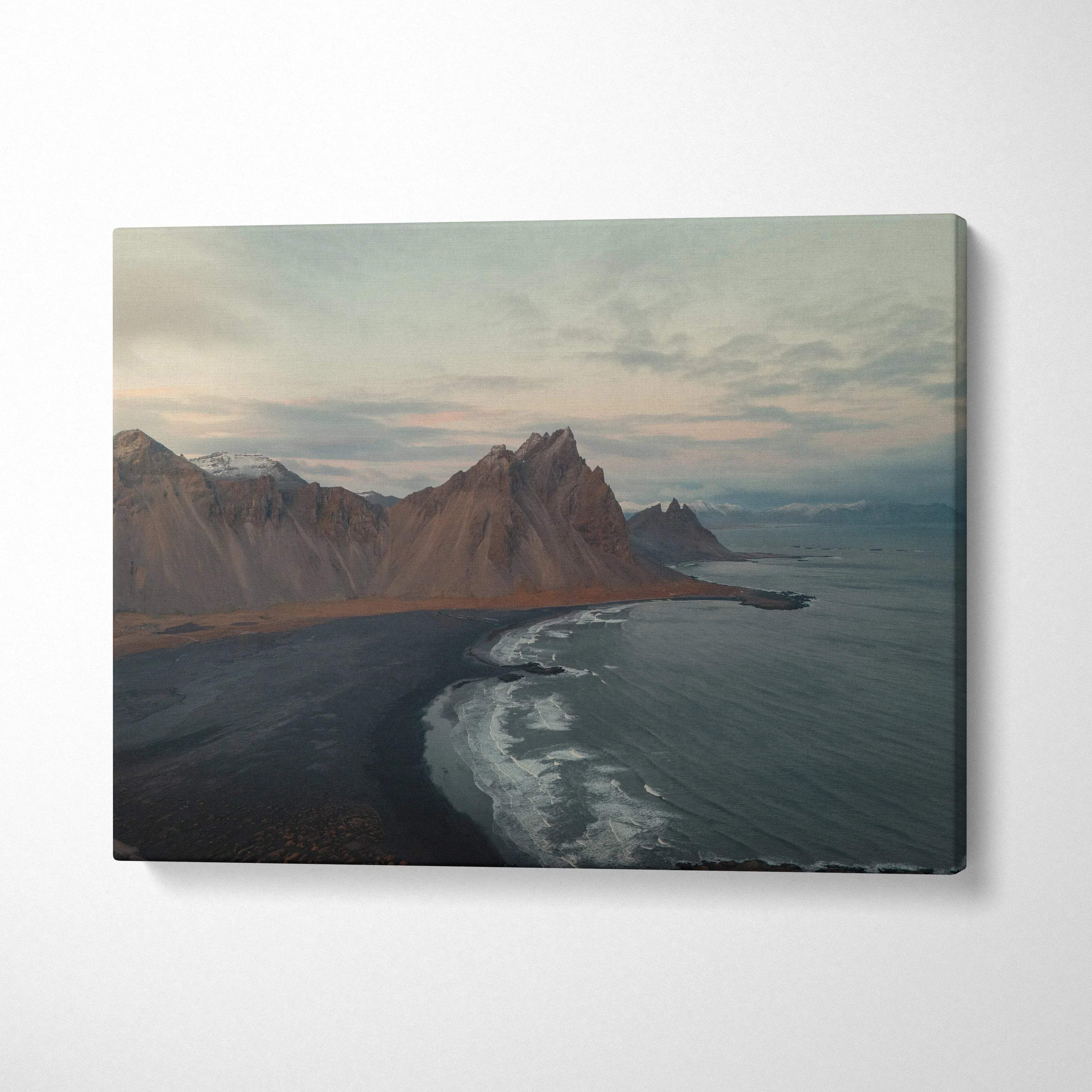 Canvas wall art featuring dramatic mountain peaks beside a dark sandy beach under a cloudy sky.