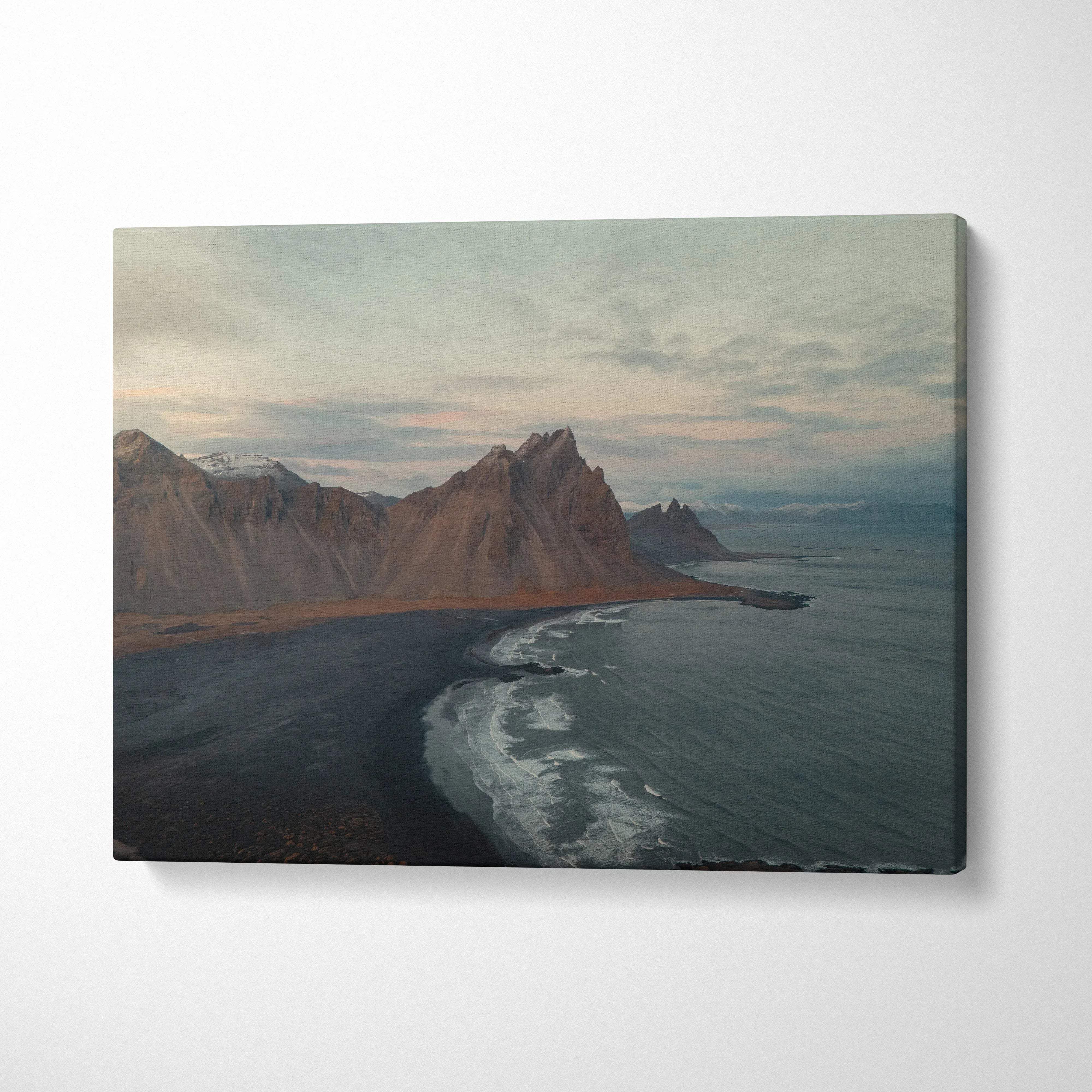 Canvas wall art featuring dramatic mountain peaks beside a dark sandy beach under a cloudy sky.