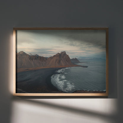 Majestic mountain range over dark shoreline with cloudy sky poster wall art in wooden frame.