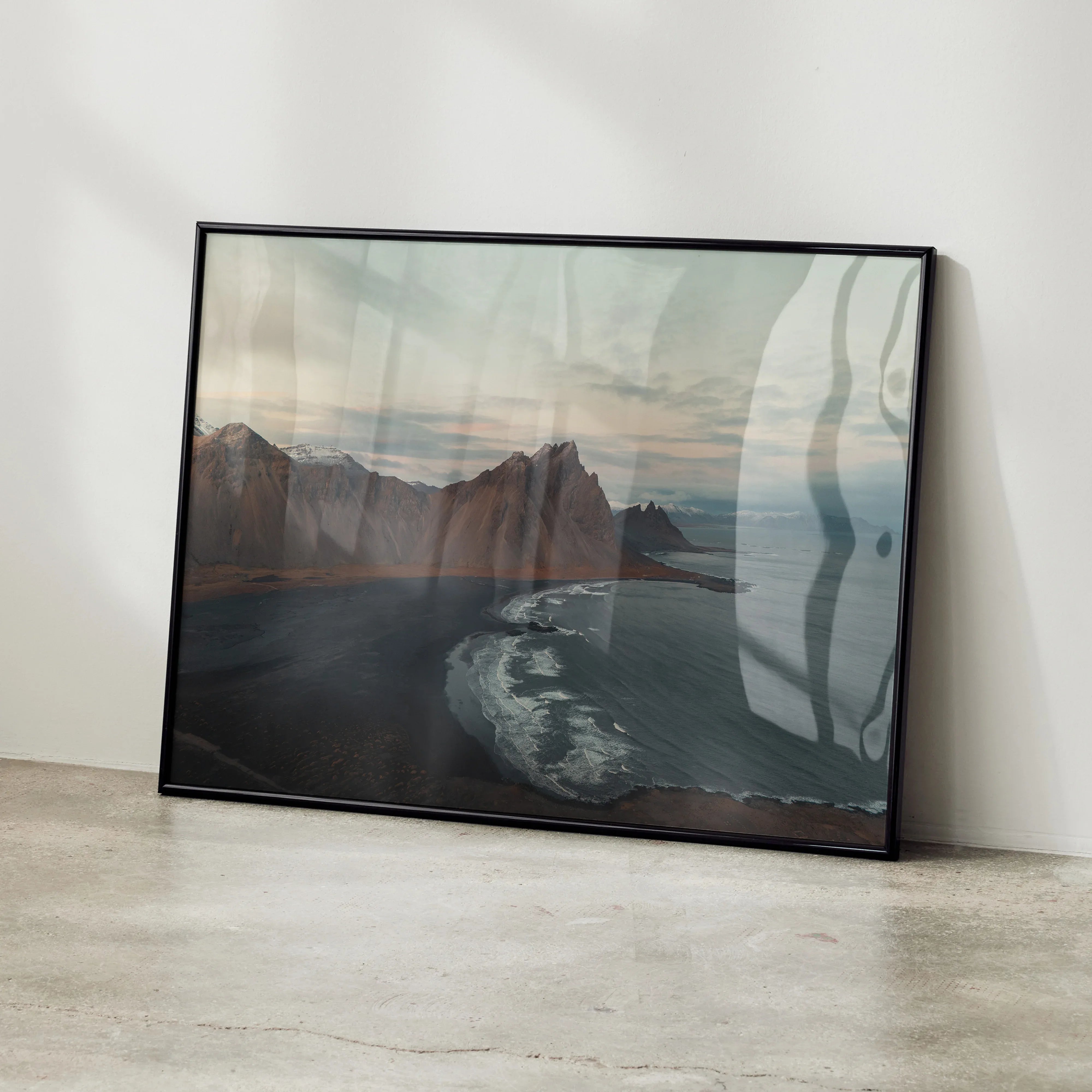 Majestic mountain landscape poster with dark shoreline and cloudy sky wall art in black frame.