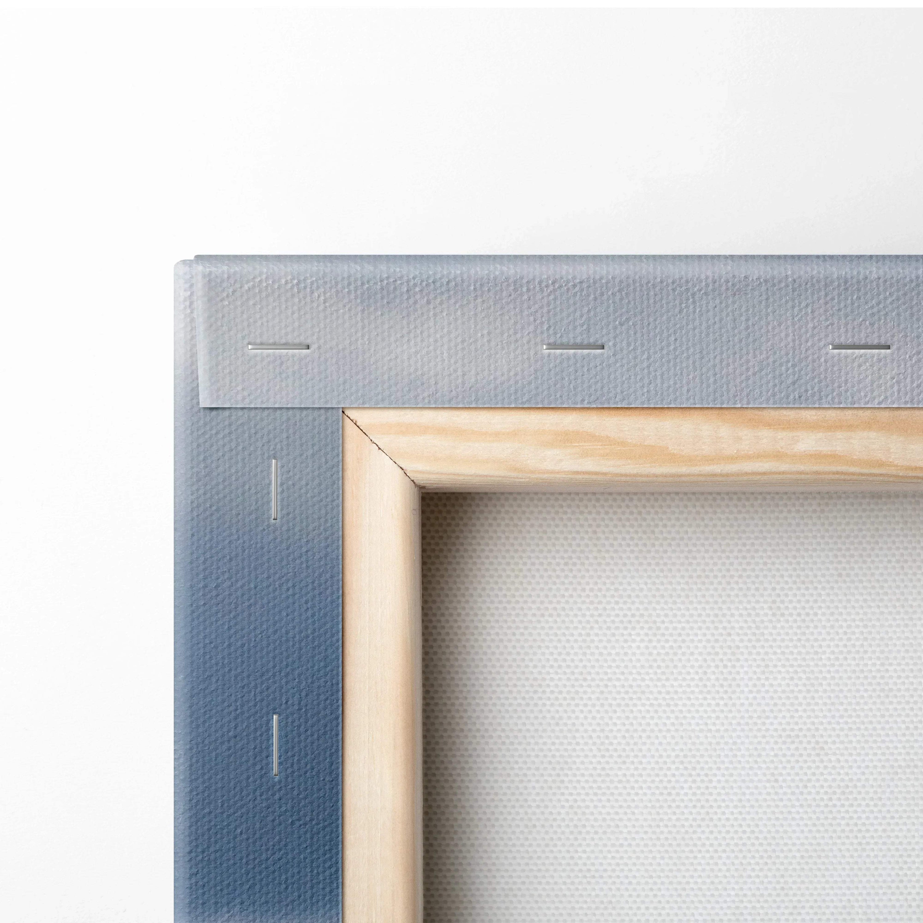 Close-up of canvas wall art corner with wooden frame and stapled edges showing mountain print on fabric.