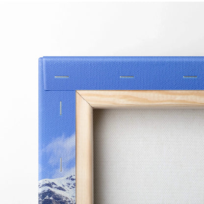 Close-up of canvas corner with blue mountain landscape print and wooden frame showing wall art texture and staples.