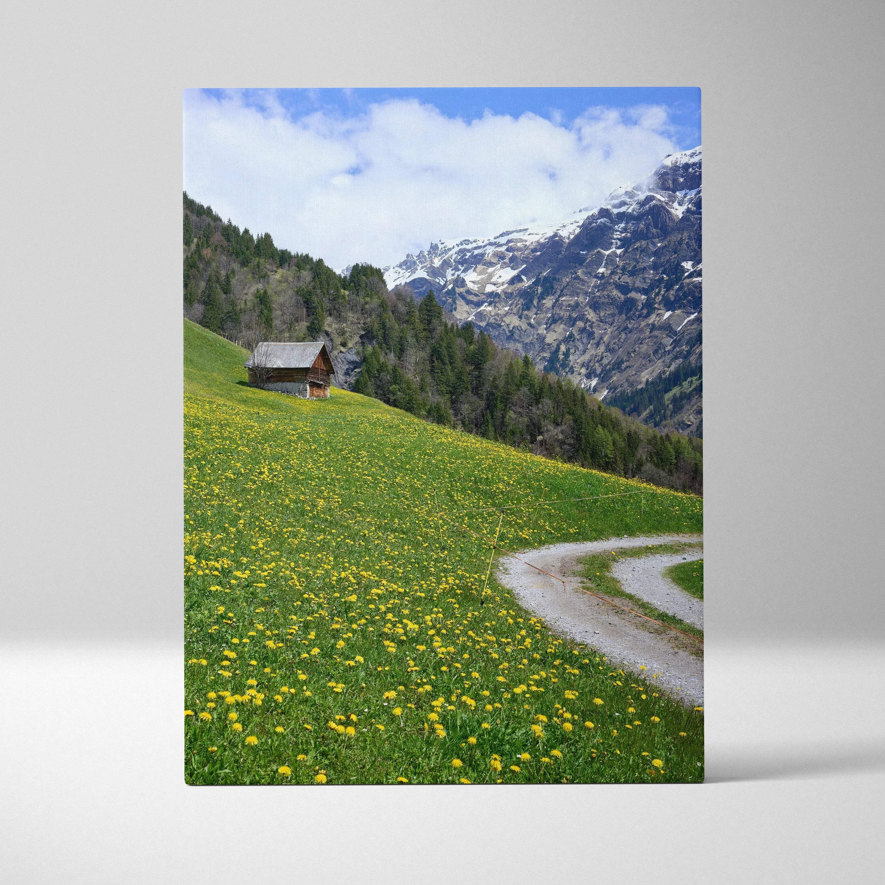 Vertical canvas wall art featuring a winding path through a yellow wildflower meadow and snowy mountain peaks.