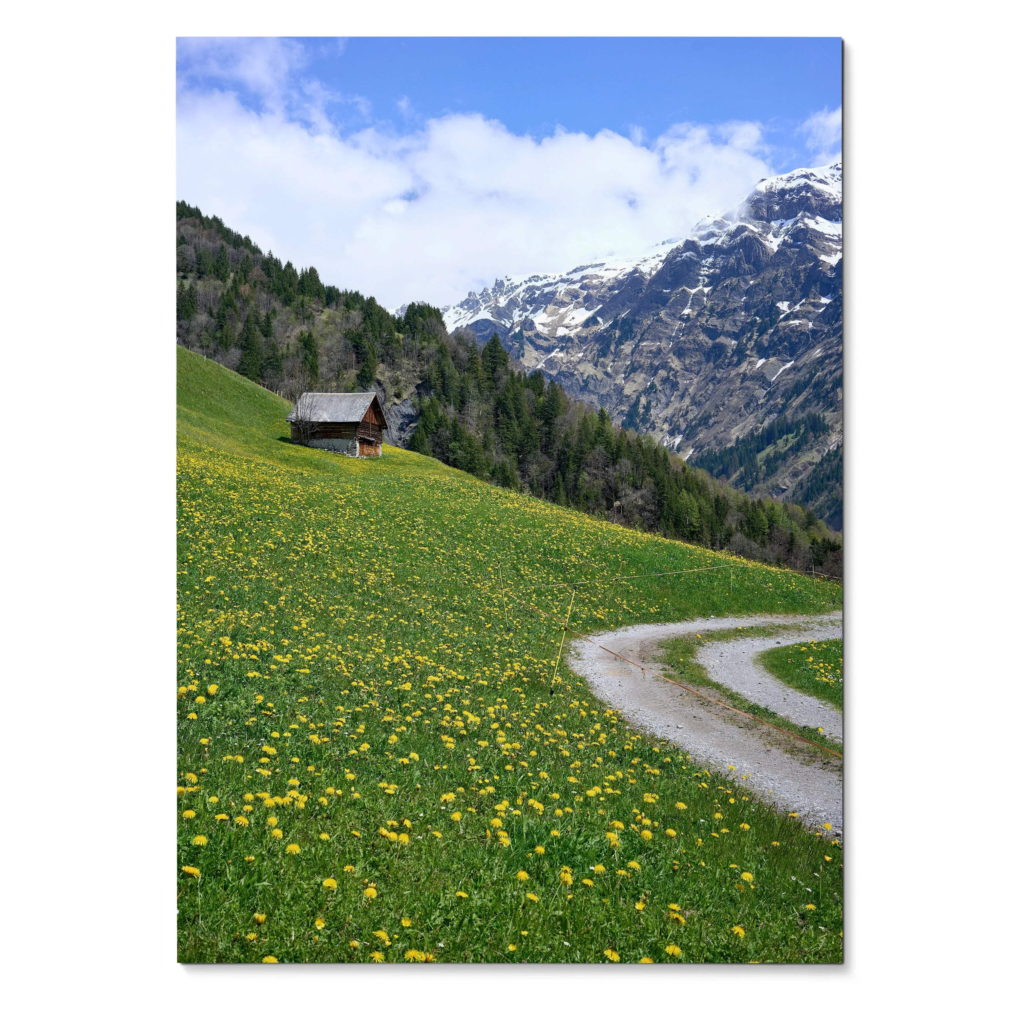 Vertical poster wall art featuring a green hillside with yellow flowers, a small cabin, and snow-capped mountains under a.