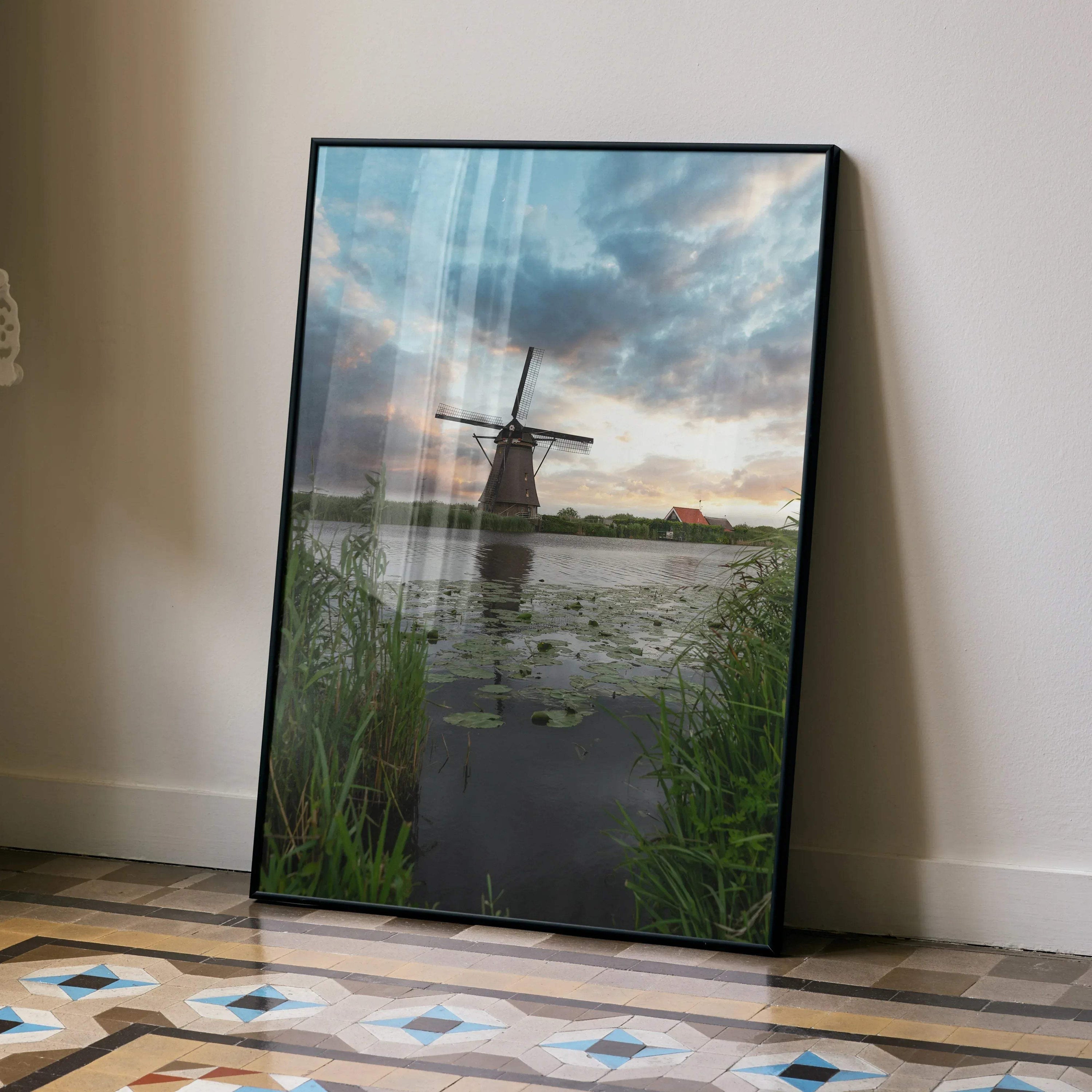 Vertical wall art poster featuring a windmill and vibrant sunset over water with lily pads and plants.