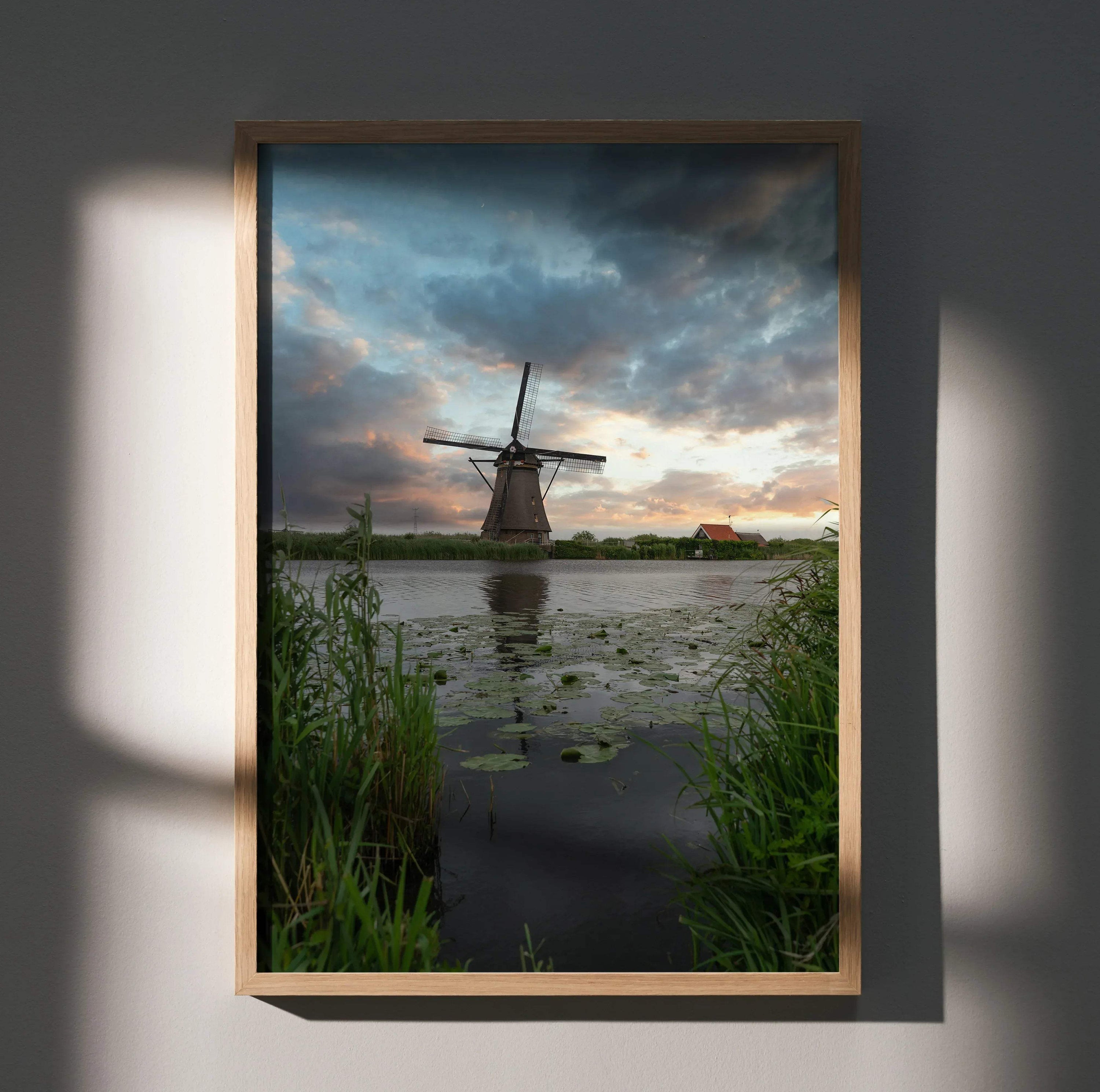 Vertical wall art poster of a windmill at sunset with dramatic clouds and reflective water.
