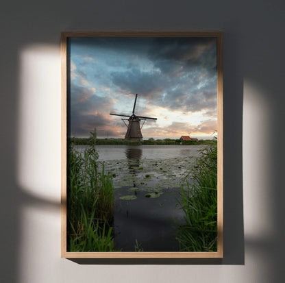 Vertical wall art poster of a windmill at sunset with dramatic clouds and reflective water.