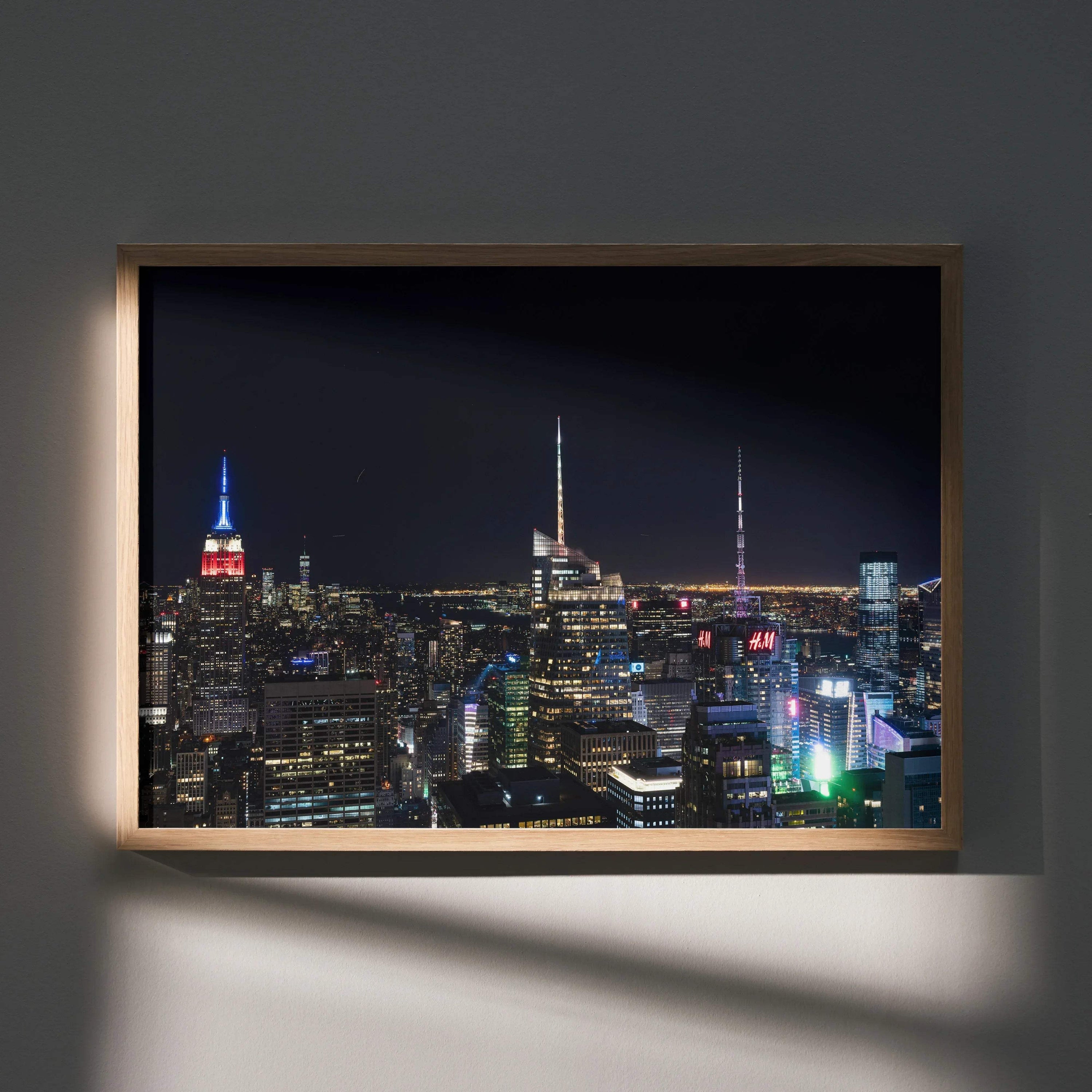 City night skyline wall art poster with illuminated skyscrapers and dark sky in wooden frame.