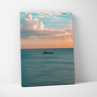 Canvas wall art featuring a tranquil ocean sunset with soft clouds and a boat on calm water.