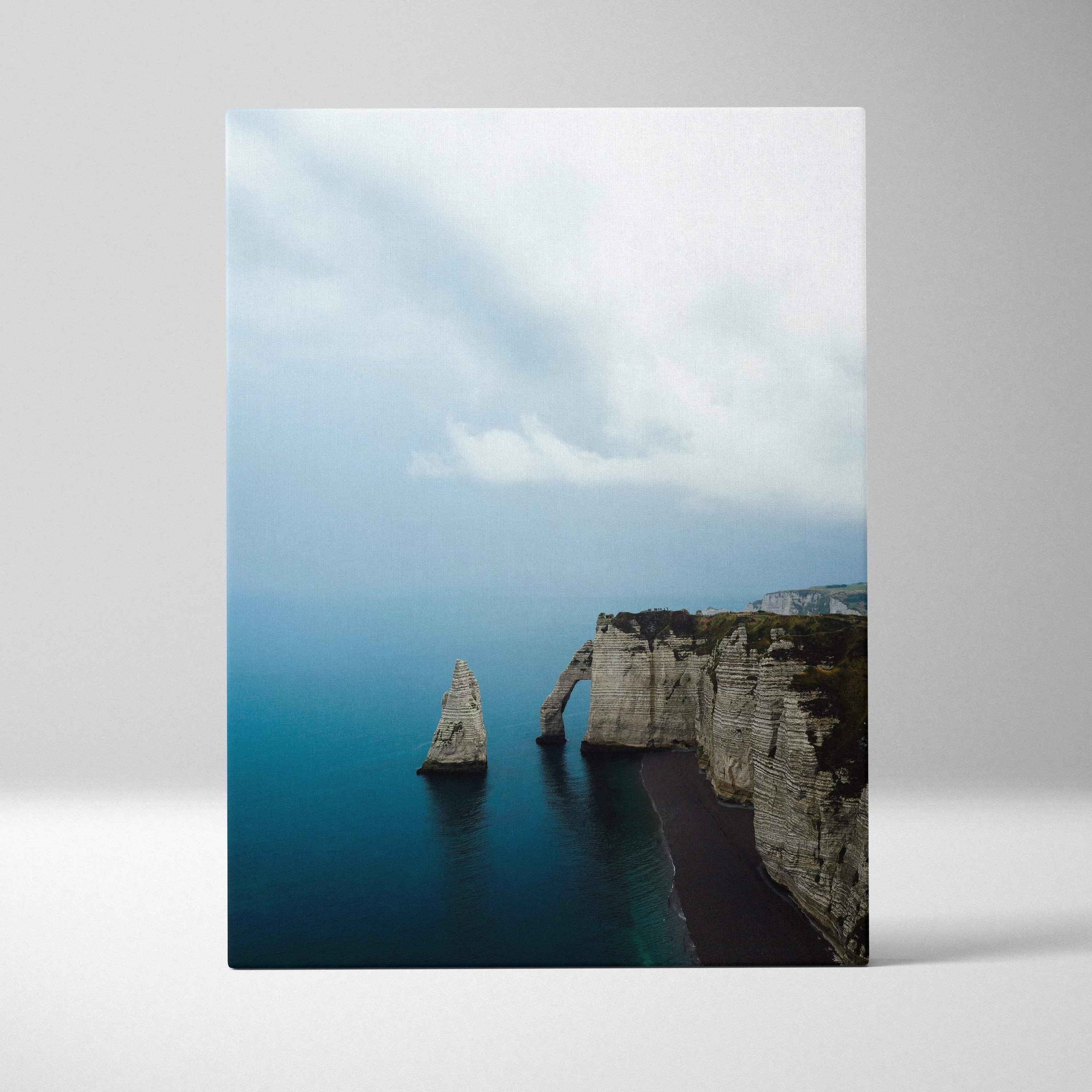 Vertical canvas wall art featuring dramatic cliffs and sea stack with a moody sky above.
