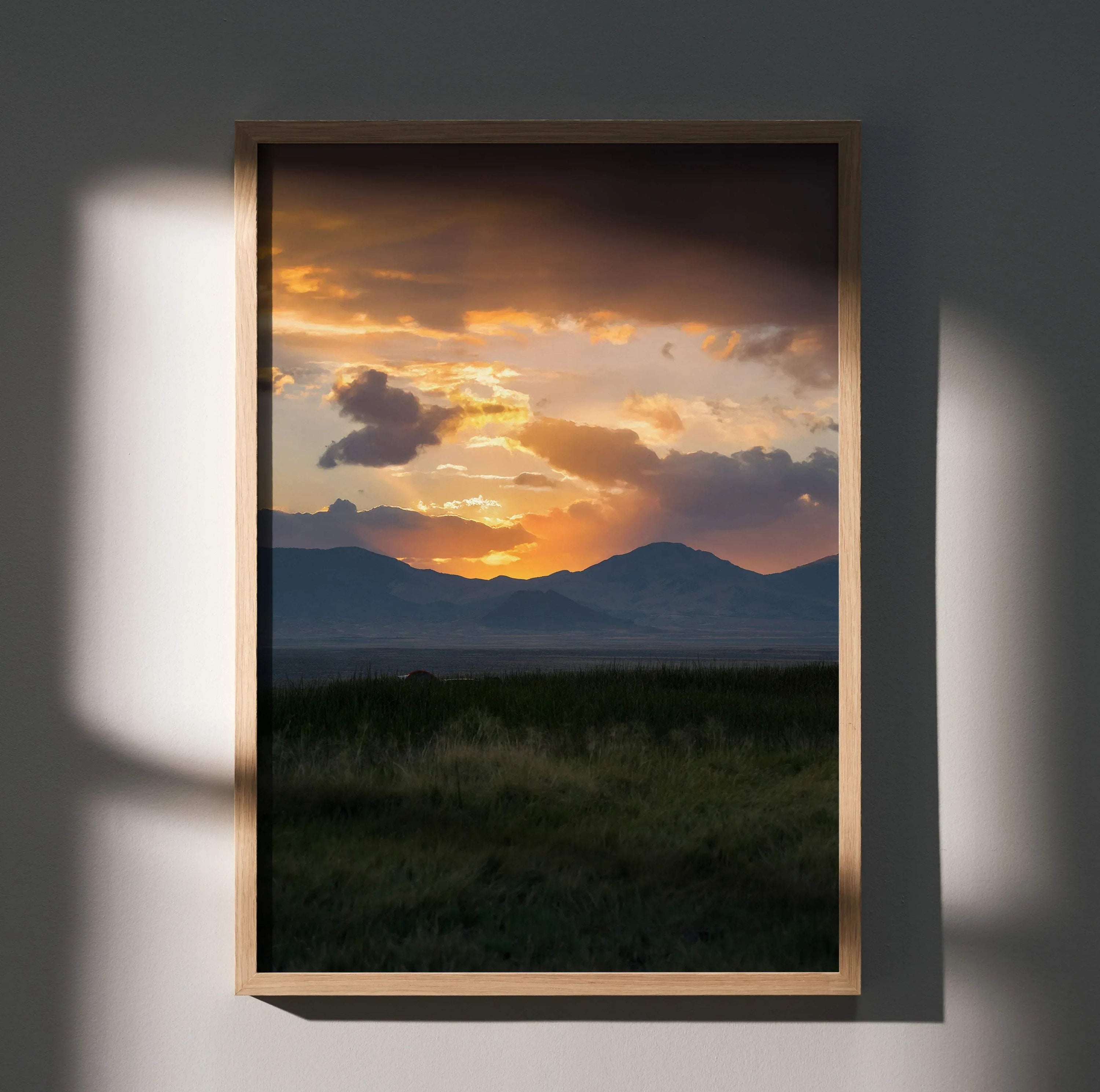 Vertical wall art poster of a mountain landscape with a dramatic orange sunset sky.