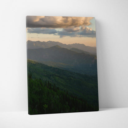 Canvas wall art featuring a serene mountain landscape at sunset with warm clouds and green forested hills.