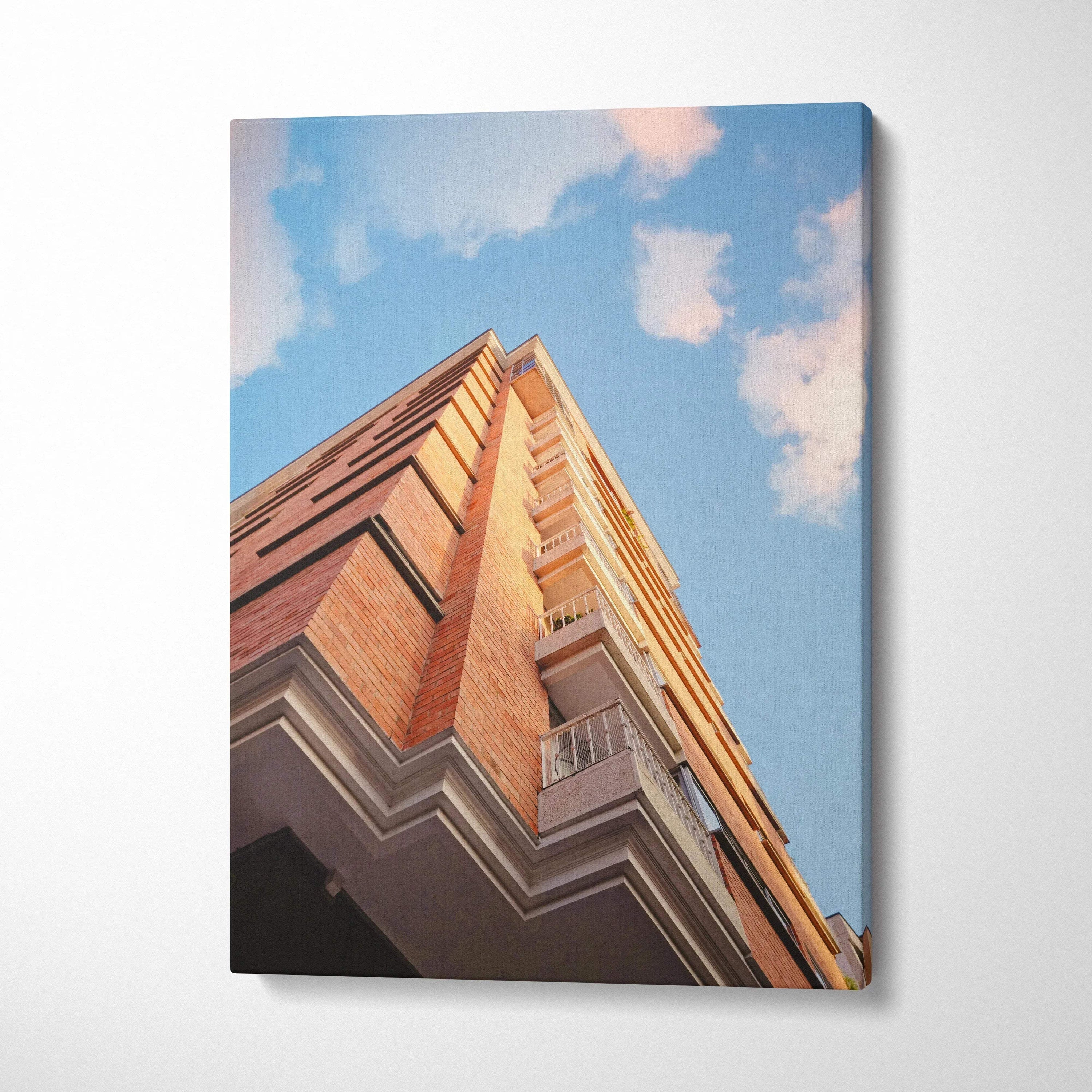 Urban architecture canvas wall art featuring a red brick building against a blue sky with clouds.