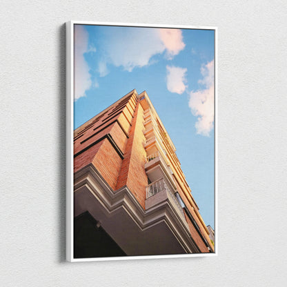Vertical canvas wall art featuring stunning red brick urban architecture against a blue sky with clouds.