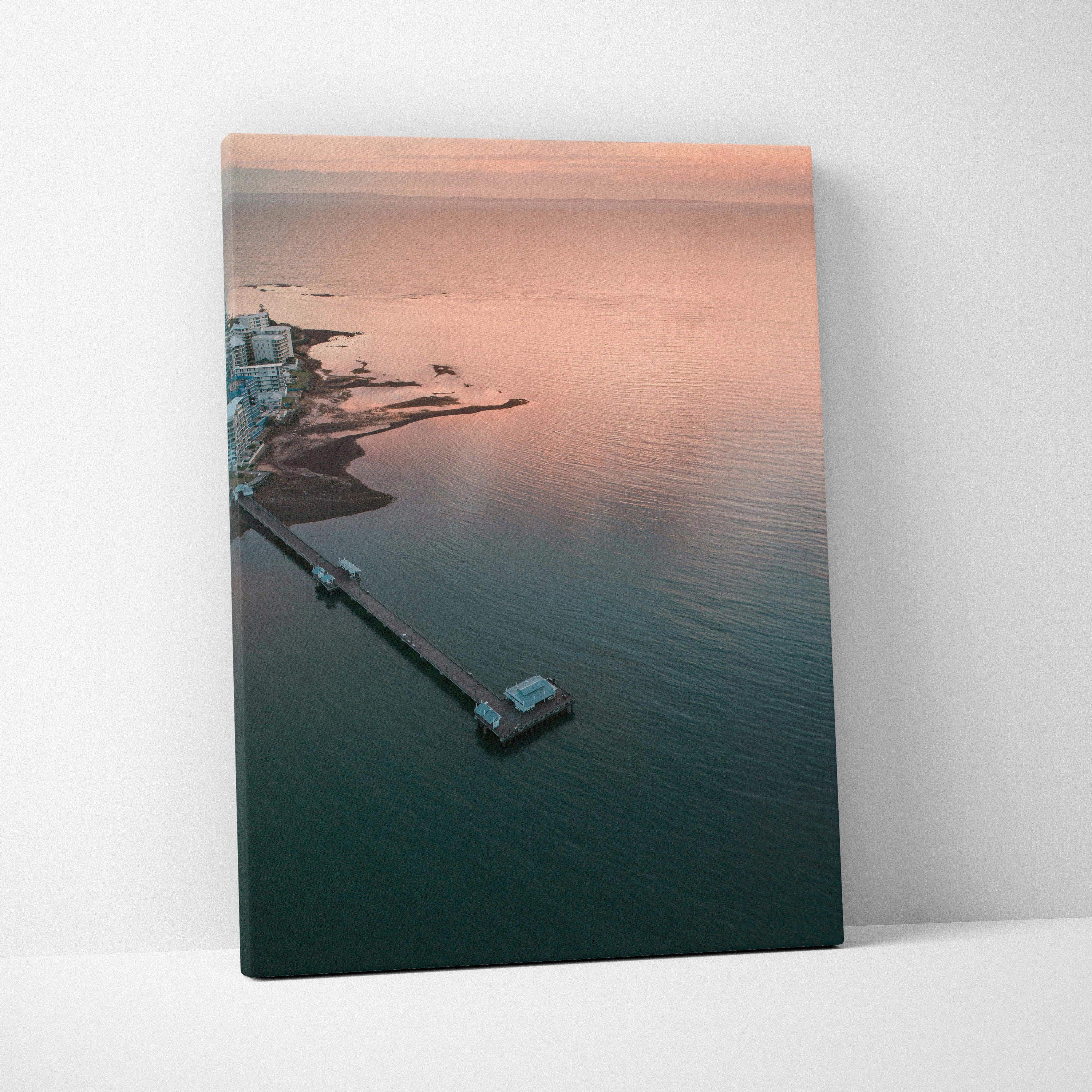Ocean sunset beach scene with pier in soft pink and blue hues canvas wall art.