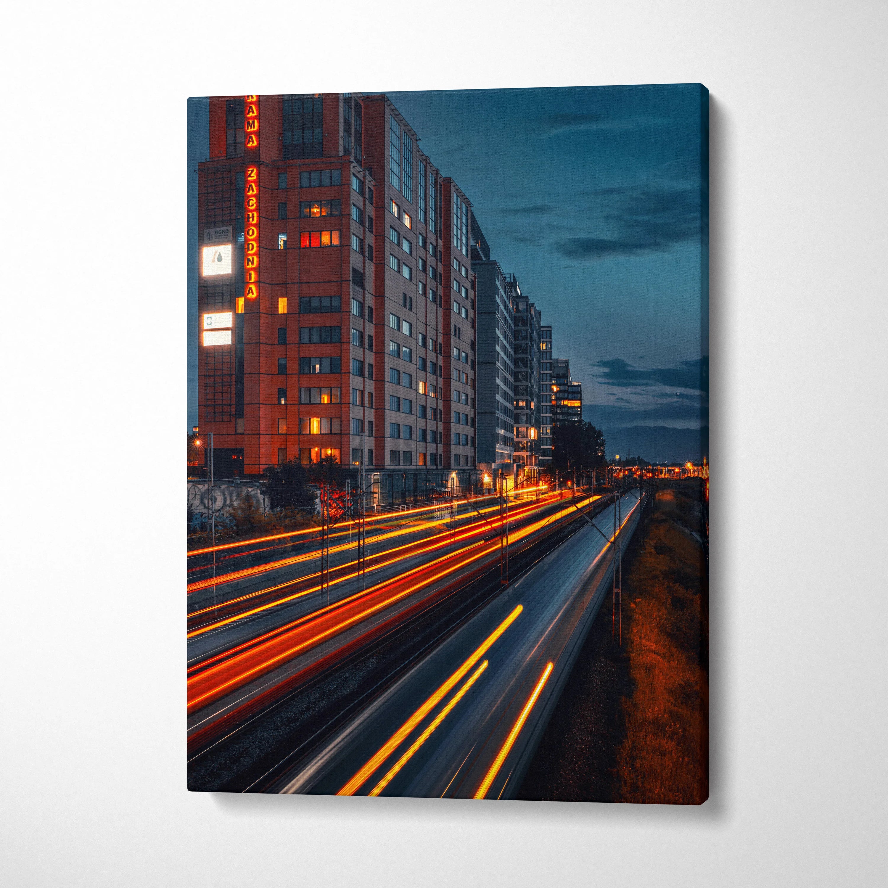 Urban cityscape canvas wall art with illuminated buildings and light trails at dusk.